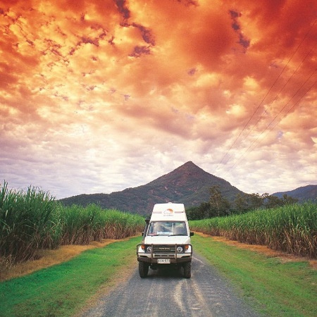 White high-top campervan driving under the fiery red sky