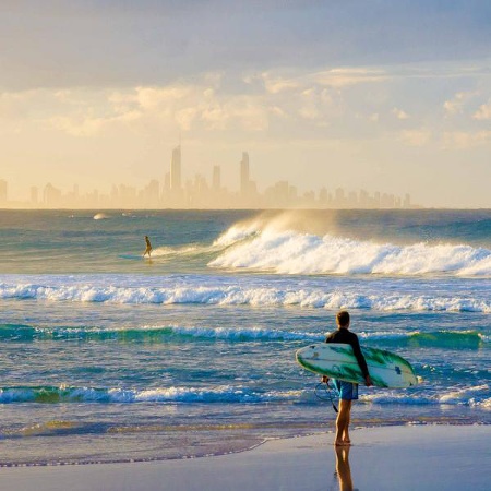 Surfers on the beach with the silhouette of the city in the distance