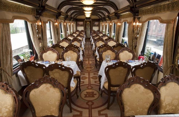  The interiro of the Russia trans train is carpeted and has wooden chairs and tables