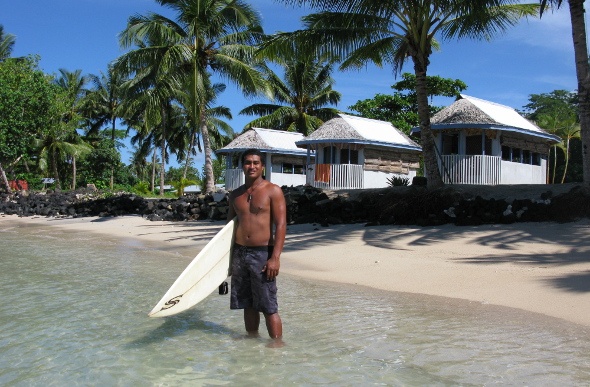 A Samoan surfer standing in ankle-deep water