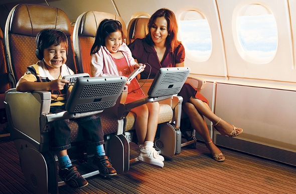  Mother and her two children playing video games in economy class 