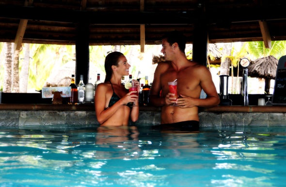Couple in the pool unwinds in the shade with their beverages