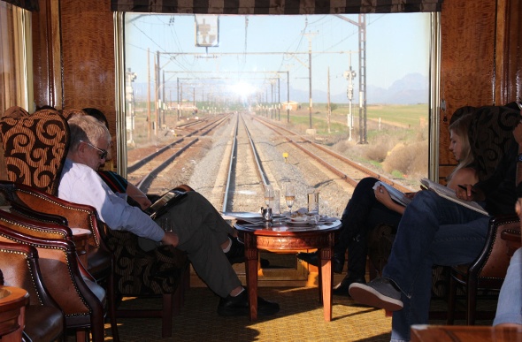  people riding the South Africa Blue Train enjoying its fancy interior with wooden tables and chairs