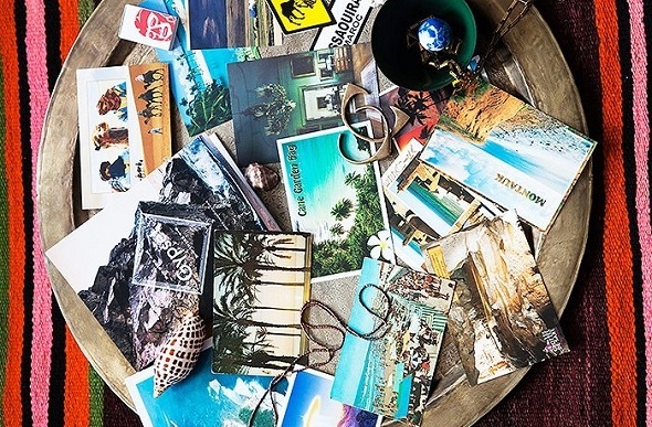 Flatlay image of a bowl of postcards and jewelry.