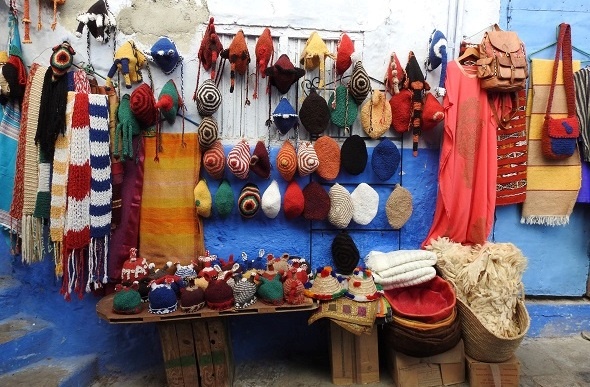  Colourful knitted beanies, scarfs and bags on display in a small market stall.