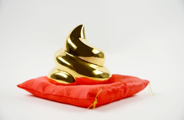 Golden poop souvenir placed on top of a mini cushion