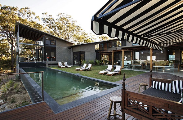  a pool with white lounge pool chairs on top of a grass filled space