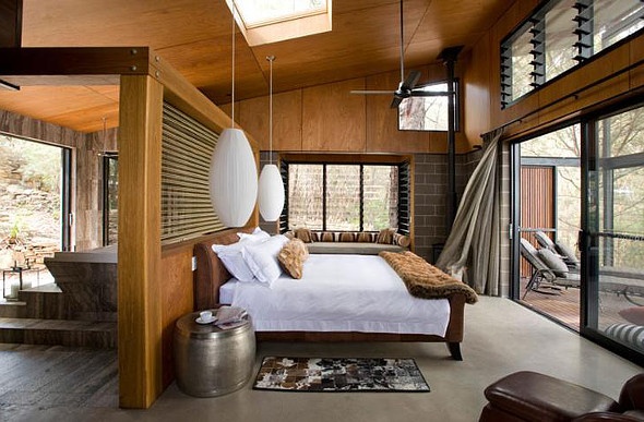 a wooden themed room with a white king sized bed and white cocoon-like hanging lamps