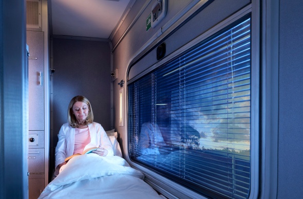  A woman relaxes with a book in her First Class sleeper carriage on board the Spirit of the Outback.