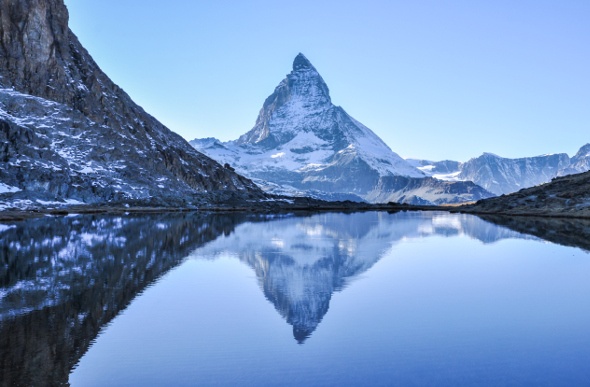  The image of the snowy pointy mountain is reflected on the water