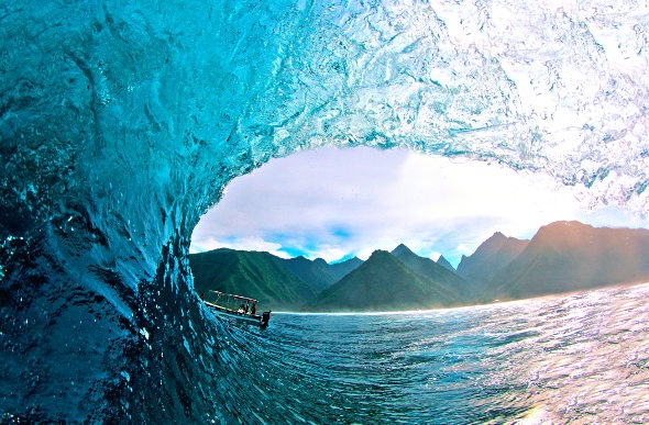 The mountainous shoreline can be seen through a curling wave at Teahupo'o in Tahiti.
