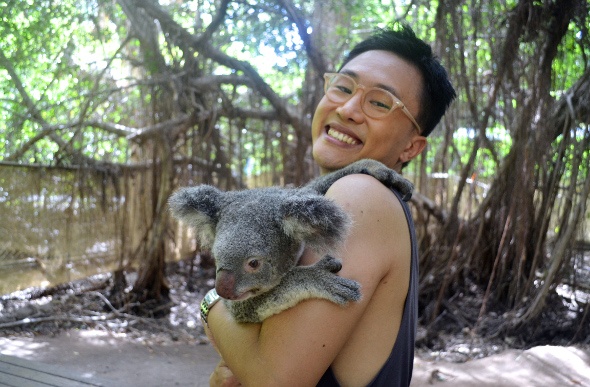 Man happily holding a koala in its sanctuary