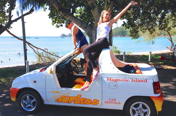 Couple posing on top of a rental car near the beach