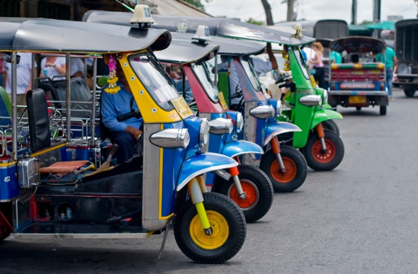  Different coloured tuk tuk lined up on the street waiting for passengers