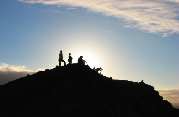  Silhouette of people hiking on a mountain with the sun on the background