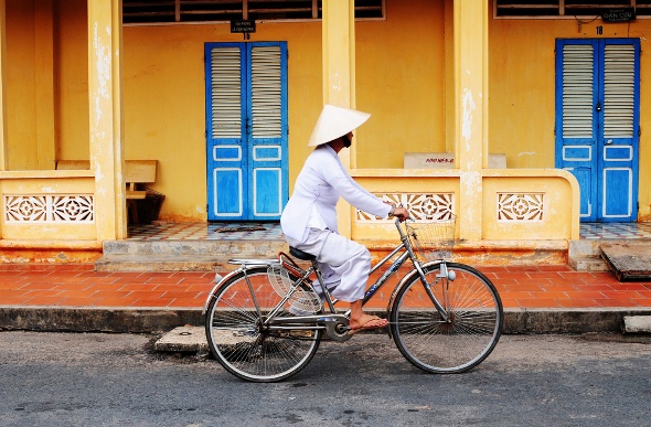 Local Vietnamese in traditional clothing cycle around town
