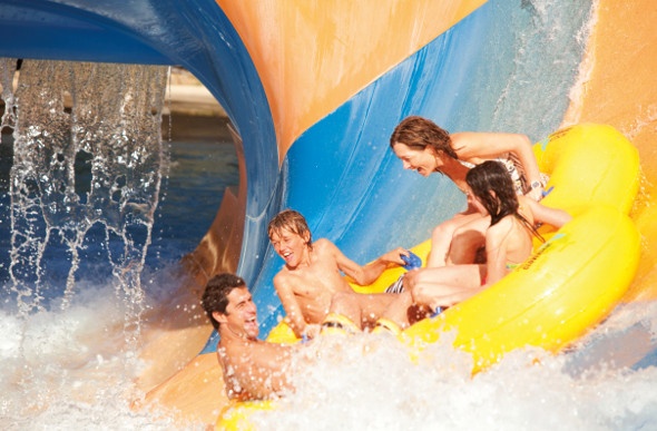  Family of four riding an inflatable in a waterpark slide