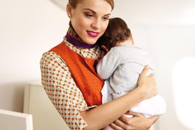 An Etihad Flying Nanny holding a young baby