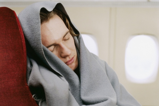 Man sleeping in an airplane tucked in a blanket