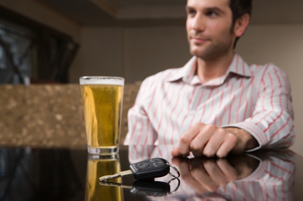 A man sitting at a table with a beer and car keys