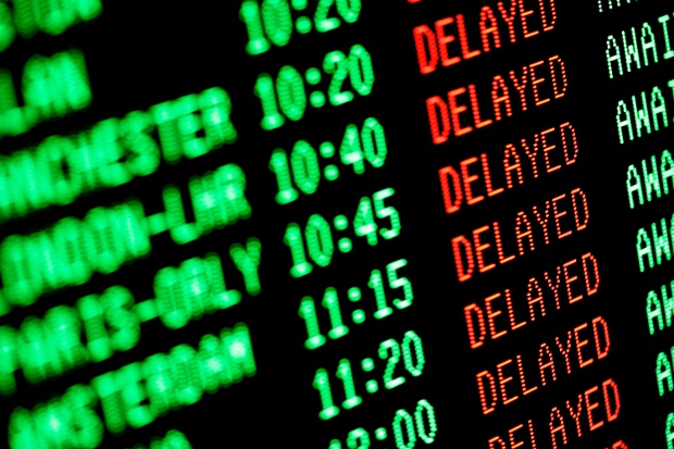 A flight board at the airport with flights showing they're delayed