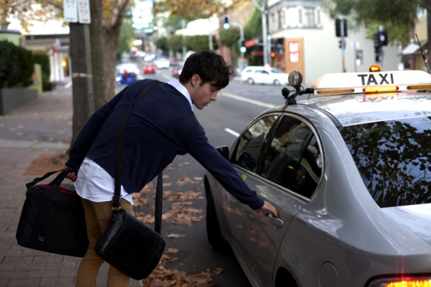 A man getting inside the taxi on the side of the Road