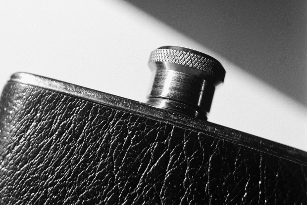 Close-up shot of a stainless steel alcohol flask with a black leather cover