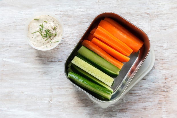 Vertically sliced carrots and cucumbers in a container with a dipping sauce