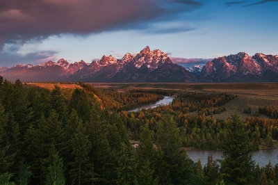 Mountain landscape alongside a river and green trees 