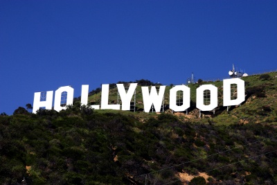 A view of the white Hollywood sign against the grass and blue sky