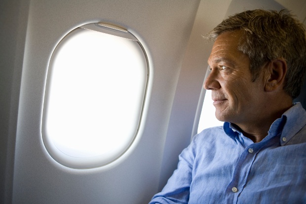 A man looking out the window of an airplane with a slight smile