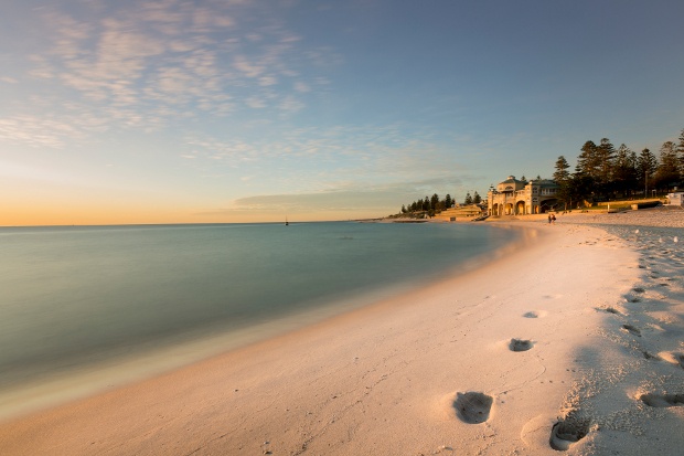 foot prints on the white sand of the crystal clear beach in perth