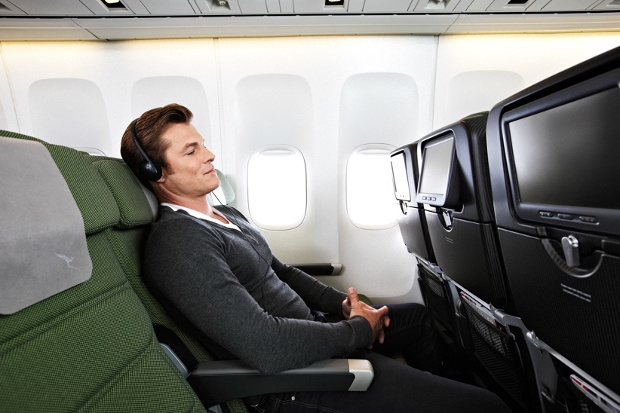 A guy listening to music while seated at the Economy class of Qantas Airline