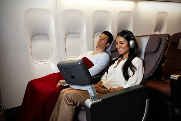 A passenger in premium economy watching their entertainment screen