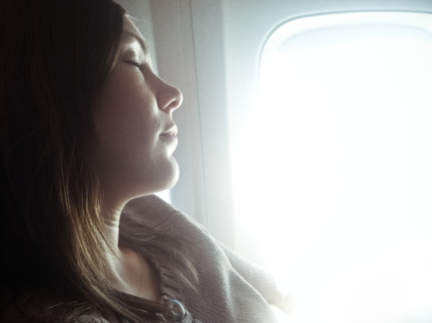 Bright window light shining down on a sleeping airline passenger