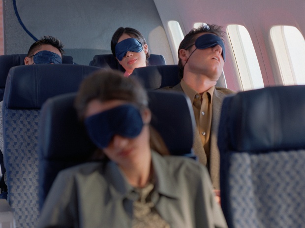Passengers on an airplane sleeping with eye mask on