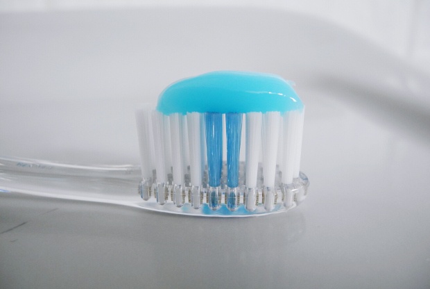 transparent toothbrush with white and blue bristles topped with toothpaste