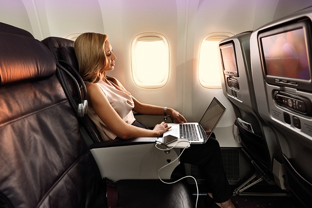 a blonde woman working comfortably on her laptop while in a flight 