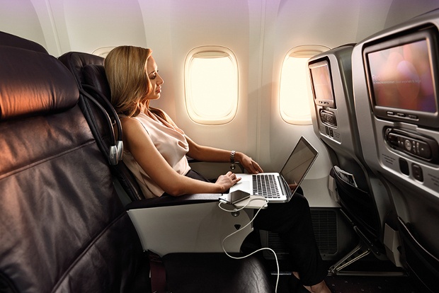 a blonde woman working comfortably on her laptop while in a flight