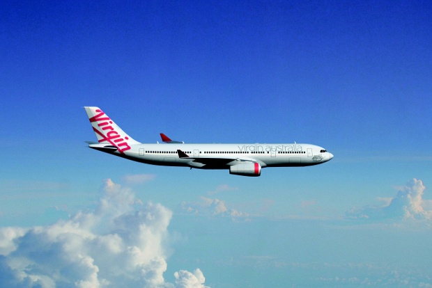 Virgin Australia plane flying in the blue sky with white cotton-like clouds on the backgroundn