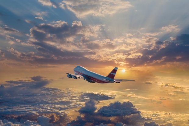 A Virgin Australia plane flying in the midst of a cloudy sky during sunrise