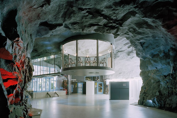 A view of an underground room looking up at a floating glass meeting room