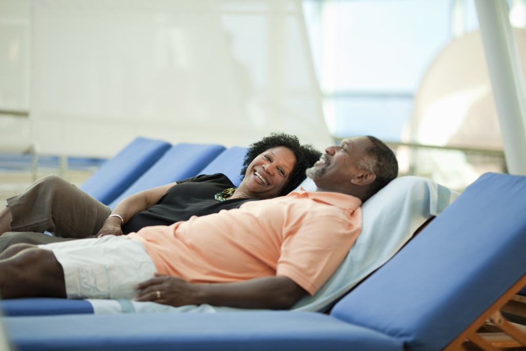 black couple enjoys sunbathing on the reclining chairs of the cruise ship