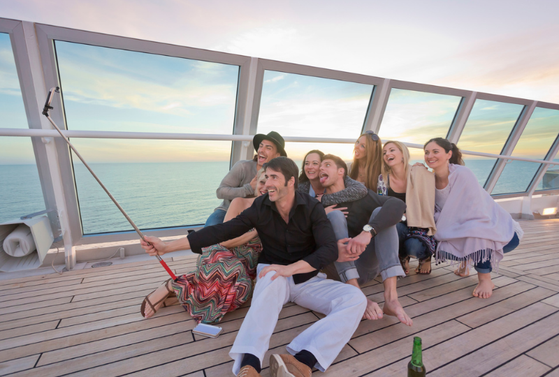 a group of people taking a picture with a selfie stick on a cruise ship deck