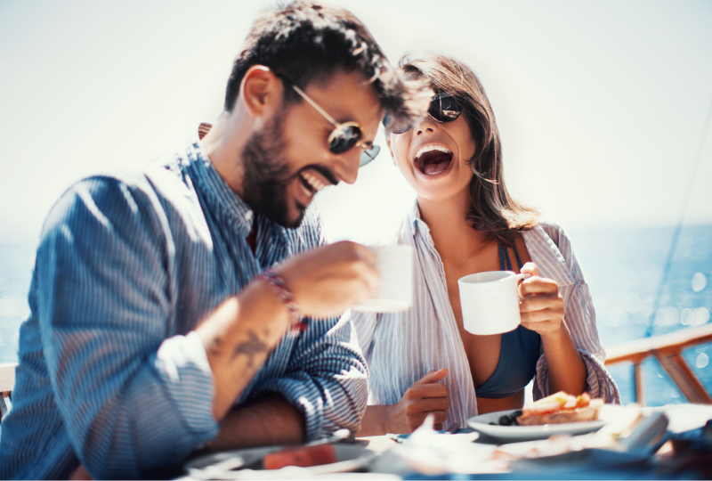 Couple drinking tea while laughing on the deck of a ship