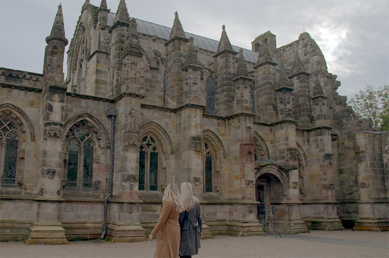 Two women walk around Rosslyn Chapel.