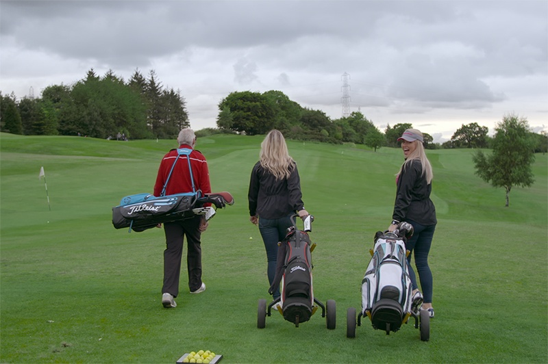 Three people play golf in Scotland.