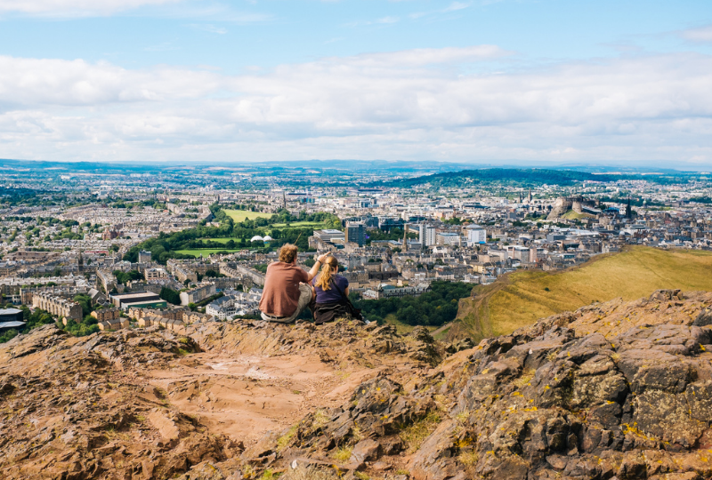 Couple sitting on top of the mountain enjoying the view of Edinburgh