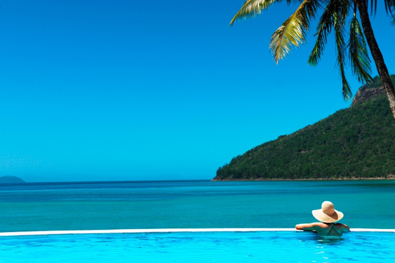 Woman in pool, overlooking the ocean from the pool edge at Hamilton Island.