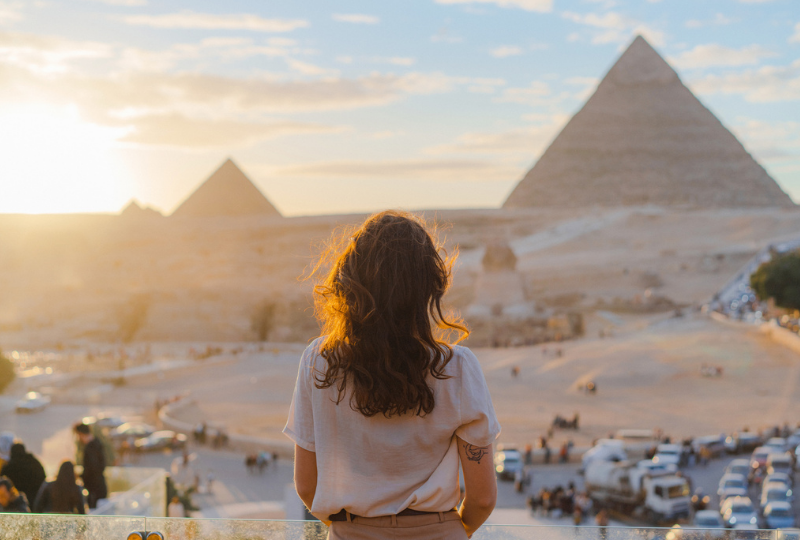 Woman standing on the terrace on the background of Giza pyramids